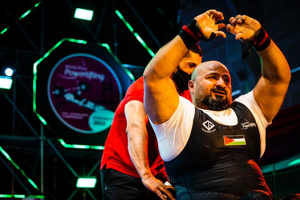 Jordanian para powerlifter in a black national uniform raising his arms