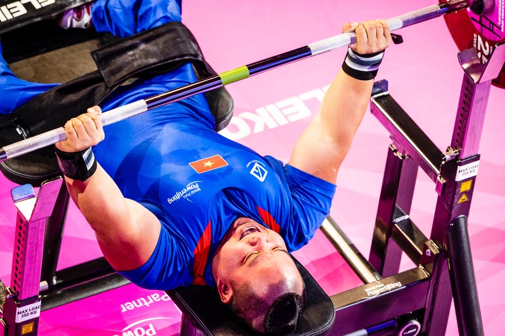 Vietnamese para powerlifter in a blue national uniform pressing the bar