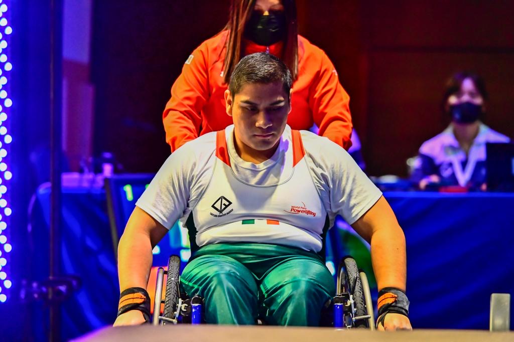 Mexican para powerlifter in a white and green national uniform focusing before competition