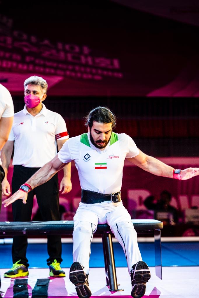 Iranian para powerlifter in a white national uniform at the competition bench