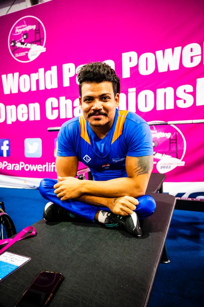 Para powerlifter in a blue competition uniform seated on the bench